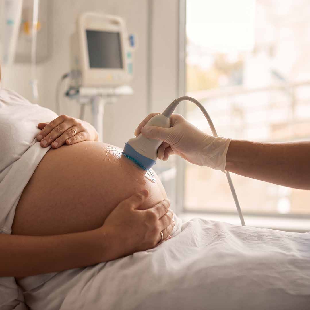 Una profesional de la salud realiza una ecografía a una mujer embarazada.